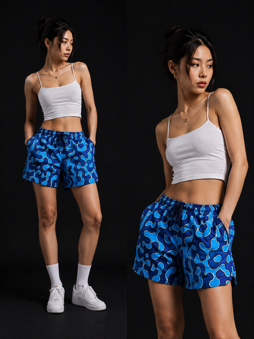 Model wearing DEEDA blue Ankara print shorts with elasticated waistband and side pockets, shown in two poses.